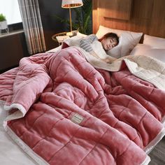 a person laying in bed with a pink blanket on top of it and a white pillow