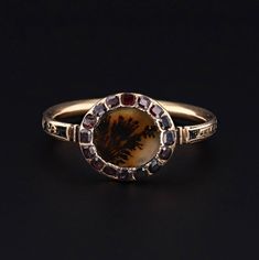 "A beautiful mourning ring from the Georgian era! This special antique treasure commemorates the passing of Thomas Ogilvy in 1766. The face of the 18k gold ring features a dendritic agate encircled by flat cut garnets. The band has black enamel and reads: \" Thos. Ogilvw Ob. 19 Nov. 1766 A: 28.\" The ring is a size 8.75 and cannot be re-sized. It is in good condition for its age; however, one of the garnets is chipped and the black enamel shows heavy signs of wear. We have many other fantastic o Victorian Ceremonial Rings With Gemstones, Stone Flowers, Georgian Ring, Georgian Jewelry, Georgian Era, Jewelry Post, Garnet Jewelry, Dendritic Agate, 18k Gold Ring