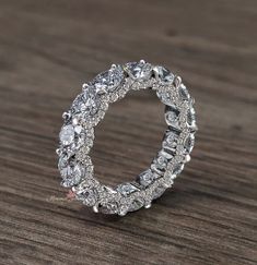 a diamond ring on top of a wooden table with the center surrounded by smaller diamonds