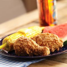 fried chicken, watermelon and corn on the cob are sitting on a plate