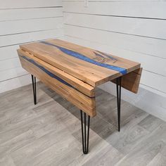 a wooden table with hairpin legs in front of a white wall and wood floor