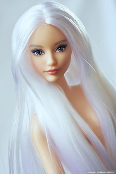 a doll with long white hair and blue eyes is posed for the camera on a white background