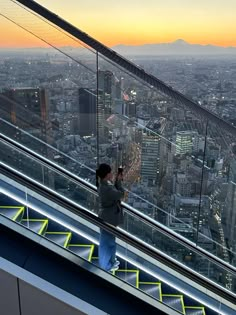 a person standing on top of an escalator looking down at the cityscape