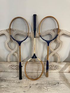 three tennis racquets on display in front of a white painted headboard