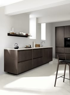 a modern kitchen with white walls and wooden cabinets, counter tops, and bar stools