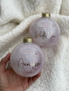 two pink ornaments with writing on them in someone's hand