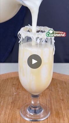 milk being poured into a glass on top of a wooden table