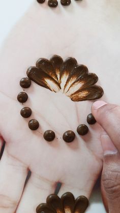 two hands are holding some chocolate chips in the shape of a heart and flowers on their palms