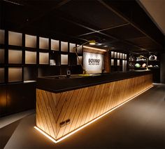 the interior of a modern office building with wood paneling and black counter tops, illuminated by recessed lighting