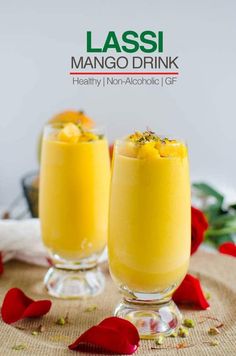 two glasses filled with mango drink and garnished with flowers on a tablecloth