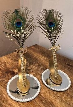 two vases with peacock feathers on them sitting on top of a wooden table next to each other