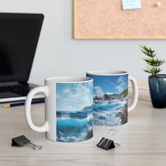 two coffee mugs sitting next to each other on a desk with a laptop in the background