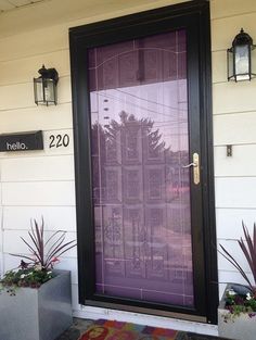 the front door of a building with two planters and a welcome mat on it