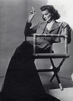 a black and white photo of a woman sitting in a chair with her hand up