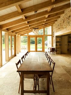 a large wooden table sitting in the middle of a room with lots of windows and doors