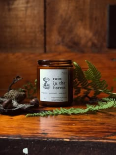 a candle sitting on top of a wooden table next to a fern leaf and rocks