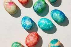 several different colored eggs sitting on top of a white surface with blue and red designs