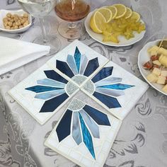 a table topped with plates and bowls filled with different types of food next to wine glasses