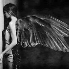 a woman with wings standing next to a wall