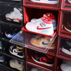 many pairs of shoes are stacked on plastic bins in a storage area with clear drawers