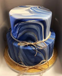 a blue and white marble cake sitting on top of a wooden plate with twine