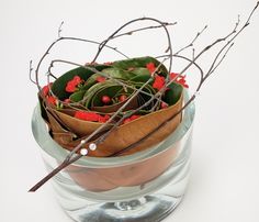 a vase filled with flowers and branches on top of a table