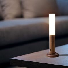 a wooden table with a lit candle on it in front of a couch and coffee table