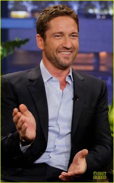 the actor is smiling while sitting down in front of a tv screen with his hands out