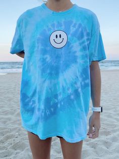 Black & white smiley face screen printed onto a Gildan t-shirt. The tie dye color is blue and purple and it is called "wildflower". This fun tee is perfect to throw over your bathing suit on a beach day. ✰ MODEL INFO: ✰ Height: 5'4" Size: normally wears a small, but is modeling a large for an oversized look. ★ MATERIAL: ★ 50% cotton, 50% polyester Tie Dye Retro Smiley Face T-Shirt, Summer Tee, Gift for Her, Trendy Aesthetic Happy Smile T-Shirt Preppy Shirt Cheap, Cheap Summer T-shirt With Rainbow Print, Cheap Cute Summer T-shirt, Cheap Tie Dye Tops For The Beach, Cheap Smiley Face Tops, Cheap Themed Blue T-shirt, Cheap Spring T-shirt With Splicing, Cheap Trendy Shirt For Spring, Cheap Simple Spring T-shirt