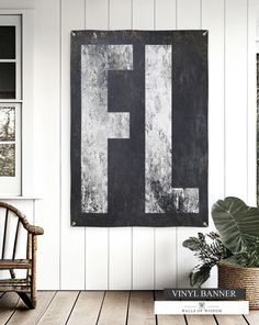 a black and white painting hanging on the wall next to a chair with a plant