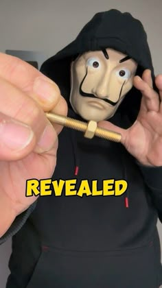 a person with a fake face holding a pen in front of their face and the words revealed above it