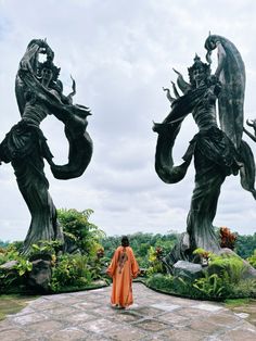 a woman standing in front of two statues