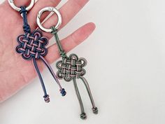 someone is holding two different key chains in their hand, one has a knot on it