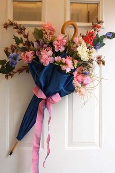 a bouquet of flowers is hanging on the front door with an umbrella attached to it