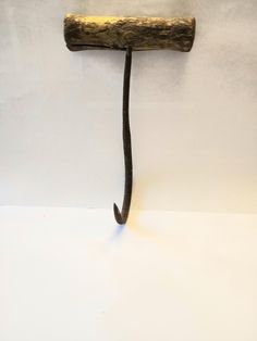 a metal hook with a wooden handle hanging from it's side on a white wall