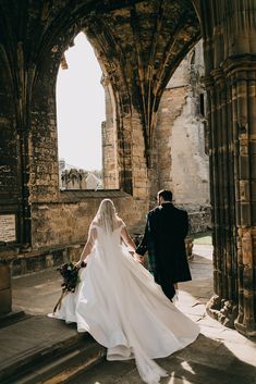 a bride and groom walking through an old building