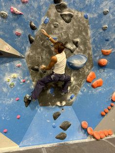 a man climbing up the side of a rock wall in an indoor climbing gym area