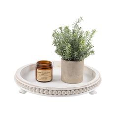 a small potted plant sitting on top of a white tray next to a candle