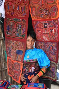 a woman standing in front of some colorful cloths