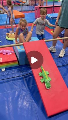 children playing on an indoor trampoline course with toys and people in the background