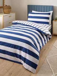 a bed with blue and white striped comforter on top of it in a bedroom