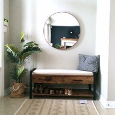 a room with a bench, mirror and potted plant on the floor in front of it