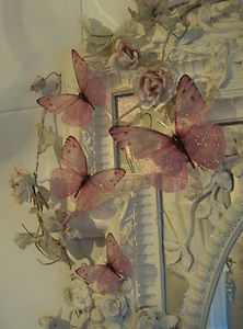 a mirror with some pink butterflies on it and flowers in front of the mirror,