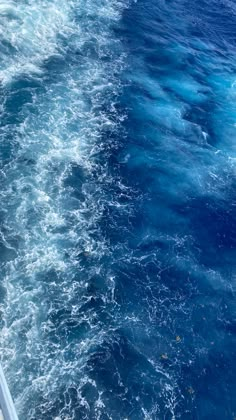 the back end of a boat traveling through the ocean with blue water and foamy waves