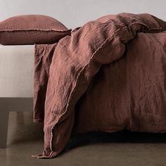 an unmade bed with brown linens and two pillows on top of the bed