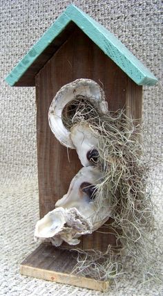 a birdhouse made out of driftwood and sea shells