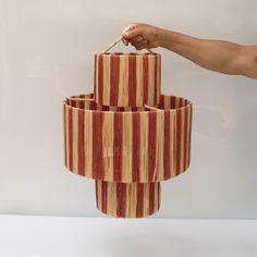 a hand is holding an object that looks like three tiered vases with sticks sticking out of them