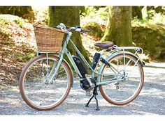 a bicycle parked on the side of a road next to some trees and grass with a wicker basket