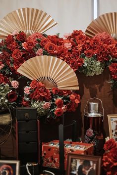 there are many red flowers on display in front of pictures and fan shaped vases