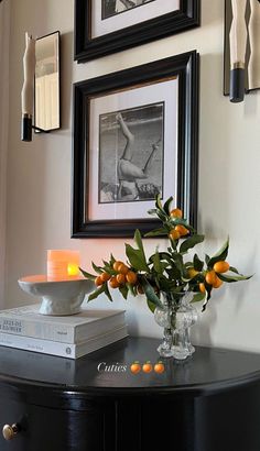 a vase filled with oranges sitting on top of a table next to a framed photo